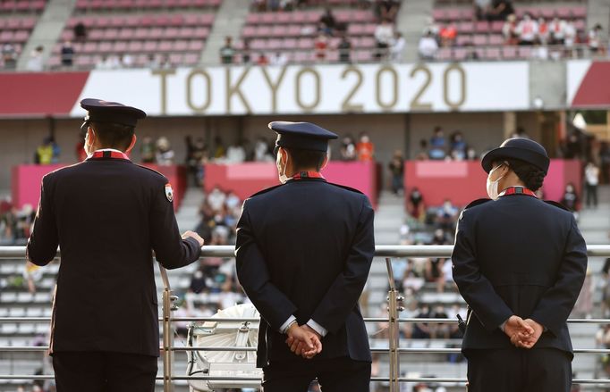 Členové bezpečnostní služby na okruhu ve Fudži sledují dojezd hromadného závodu mužů na OH 2020