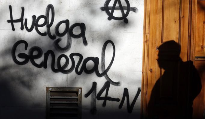 A man casts his shadow as he walks past a graffiti calling for a general strike in Madrid November 13, 2012. Spain's two largest labour unions have called for a general strike on November 14, the second against the conservative government since they took power in December and coinciding with industrial action in Portugal on the same day. REUTERS/Sergio Perez (SPAIN - Tags: BUSINESS EMPLOYMENT POLITICS CIVIL UNREST) Published: Lis. 13, 2012, 10:54 dop.