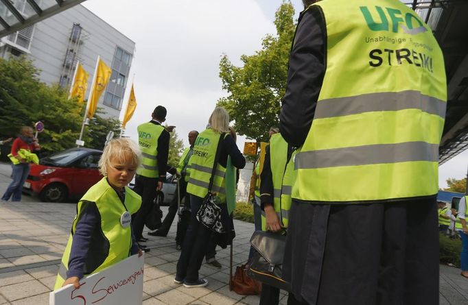 A child (L) holds a sign at a Lufthansa cabin crew union (UFO) strike rally outside Munich Airport, September 4, 2012.Deutsche Lufthansa, Germany's biggest airline, cancelled hundreds of flights in Frankfurt, Berlin and Munich on Tuesday as cabin crew launched a second round of strikes in a row over pay and conditions. The strike action follows a walkout on Friday that left 26,000 passengers stranded and caused millions of euros in lost revenues. REUTERS/Michael Dalder(GERMANY - Tags: POLITICS BUSINESS EMPLOYMENT TRANSPORT CIVIL UNREST) Published: Zář. 4, 2012, 12:40 odp.