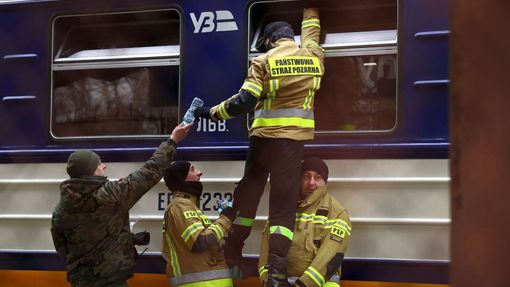 Polští hasiči podávají vodu do vlaku plného lidí prchajících z Ukrajiny.
