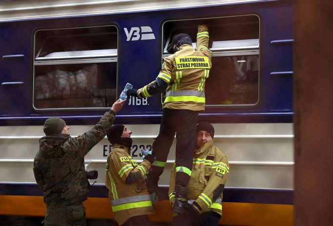Polští hasiči podávají vodu do vlaku plného lidí prchajících z Ukrajiny.
