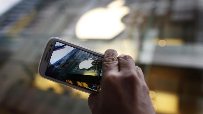 A passerby photographs an Apple store logo with his Samsung Galaxy phone on the morning iPhone 5 goes on sale to the public in central Sydney September 21, 2012. Apple In