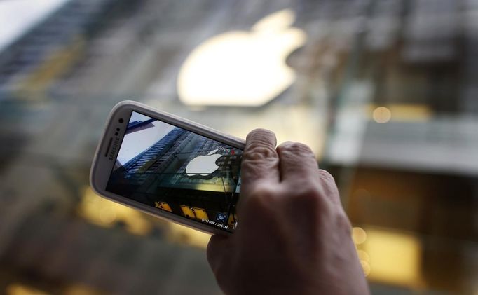 A passerby photographs an Apple store logo with his Samsung Galaxy phone on the morning iPhone 5 goes on sale to the public in central Sydney September 21, 2012. Apple In