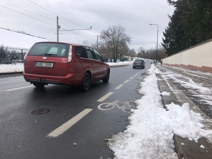 Cyklopruh v Praze v zimě, když napadá sníh. Shrnují ho na silnici... pro cyklisty problém.