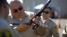 A Los Angeles County Sheriff's deputy takes in guns from motorists trading them in at the 'Gifts for Guns' gun buyback in Compton, California, January 21, 2013. People can trade in their guns anonymously and with no questions asked in exchange for $200 gift cards for assault weapons, $100 gift cards for shotguns, handguns and rifles, and $50 for non-operational firearms. U.S. President Barack Obama is pushing to address controversial issues surrounding gun violence and regulation as he begins his second term in office. REUTERS/David McNew (UNITED STATES - Tags: POLITICS SOCIETY) Published: Led. 21, 2013, 10:45 odp.