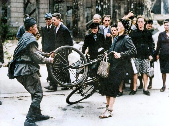 Ruský voják a německá žena v konfliktu o jízdní kolo v Berlíně, květen 1945, krátce po konci druhé světové války. Ilustrační snímek. Kolorováno