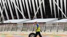 A worker pushes a tyre past the Olympic Stadium in the London 2012 Olympic Park at Stratford in London July 17, 2012. REUTERS/Luke MacGregor (BRITAIN - Tags: SPORT OLYMPICS TPX IMAGES OF THE DAY) Published: Čec. 17, 2012, 12:11 odp.