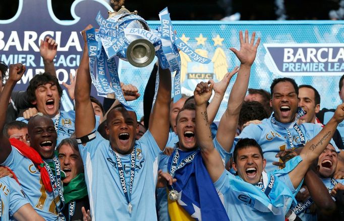 Belgický fotbalista Vincent Kompany zvedá nad hlavu trofej pro vítěze anglické Premier League, kterou získal v roce 2012 s Manchesterem City.