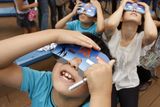 Děti v Tokiu sledují zatmění s ochrannými brýlemi.