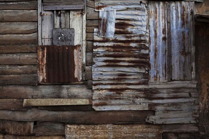 Patchwork of rusted metal sheets covers aging wooden planks on side of traditional colonial-era Board House in Freetown