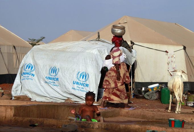 A woman walks past a child playing with water in a refugee camp in Sevare January 26, 2013. REUTERS/Eric Gaillard (MALI - Tags: CIVIL UNREST CONFLICT SOCIETY) Published: Led. 26, 2013, 6:44 odp.