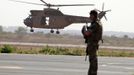 A British soldier secures the area upon the arrival of a British C17 cargo aircraft while a French Puma helicopter takes off at the Mali air force base near Bamako January 18, 2013. The British Royal Air Force is lending logistical support to France as it sends forces to Mali. REUTERS/Eric Gaillard (MALI - Tags: CIVIL UNREST CONFLICT MILITARY) Published: Led. 18, 2013, 6:17 odp.