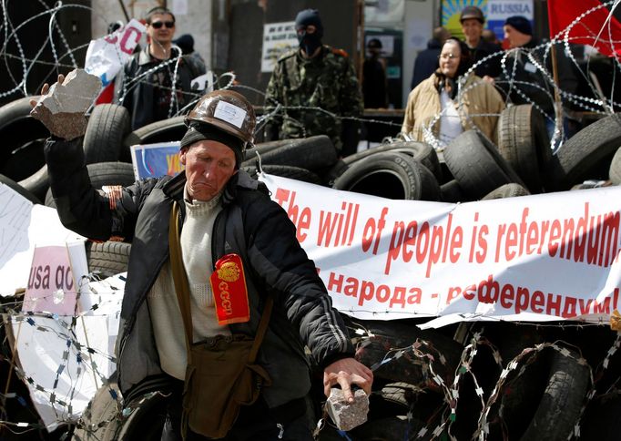 A pro-Russia protester breaks a piece of stone at a barricade outside a regional government building in Donetsk, in eastern Ukraine April 15, 2014.