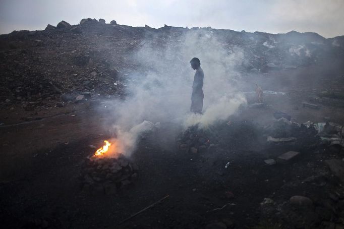 A man stands next to burning coal to make it for domestic use such as for cooking purposes at Dhanbad district in the eastern Indian state of Jharkhand September 19, 2012. With oil and gas output disappointing and hydropower at full throttle, Asia's third-largest economy still relies on coal for most of its vast energy needs. About 75 percent of India's coal demand is met by domestic production and, according to government plans, that won't change over the next five years. Picture taken September 19, 2012. To match INDIA-COAL/ REUTERS/Ahmad Masood (INDIA - Tags: BUSINESS EMPLOYMENT ENERGY SOCIETY ENVIRONMENT) Published: Říj. 21, 2012, 10:01 odp.