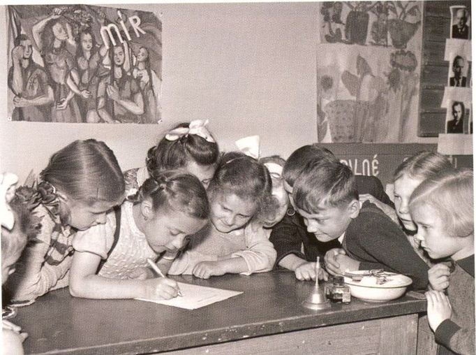 Dobová fotografie z 50. let ukazuje děti podepisující „mírový slib“ nebo rezoluci. I nejmladší žáci byli tehdy zapojováni do politických kampaní.