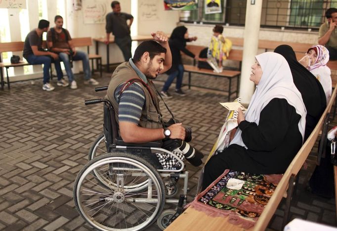 Wheelchair-bound Palestinian freelance photographer Moamen Qreiqea speaks with protesters calling for the release of Palestinian prisoners from Israeli jails, in Gaza City October 1, 2012. Qreiqea, 25, lost both his legs in an Israeli air strike in 2008 while taking pictures east of Gaza. The father of two is determined to continue his career despite his disability. REUTERS/Suhaib Salem (GAZA - Tags: MEDIA SOCIETY) Published: Říj. 1, 2012, 3:39 odp.