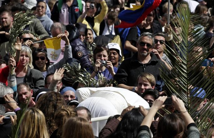 Snímek z 24. března. Papež František se sklání z Papamobilu, aby mohl políbit nemocného chlapce na invalidním vozíku. Papež se s lidmi setkal po mši na Květnou neděli na náměstí svatého Petra ve Vatikánu.