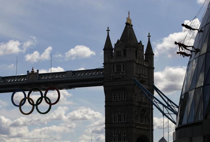 Members of the Streb extreme dance group abseil down the face of City Hall, with Tower Bridge and the Olympic rings behind them in central London July 15, 2012. The event is part of the London 2012 Cultural Olympiad, being held in the capital as it is about to host the London 2012 Olympic Games. REUTERS/Andrew Winning (BRITAIN - Tags: ENTERTAINMENT CITYSPACE SOCIETY SPORT OLYMPICS) Published: Čec. 15, 2012, 11:01 dop.