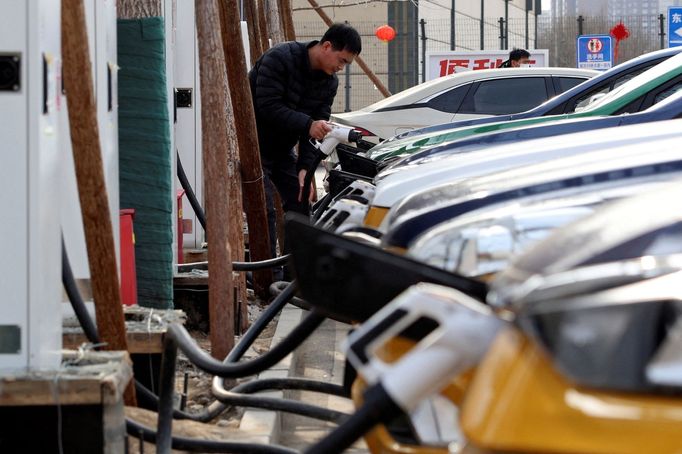 FILE PHOTO: A man holds a charging plug to charge a car at a Smart Charge electric vehicle (EV) charging station in Beijing, China February 2, 2024. REUTERS/Florence Lo/F