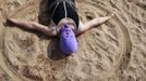 A woman, wearing a nylon mask, creates a circle in the sand as she lies down during her visit to a beach in Qingdao, Shandong province July 6, 2012. The mask, which was invented by a woman about seven years ago, is used to block the sun's rays. The mask is under mass production and is on sale at local swimwear stores. REUTERS/Aly Song (CHINA - Tags: SOCIETY ENVIRONMENT TRAVEL) Published: Čec. 6, 2012, 4:30 odp.