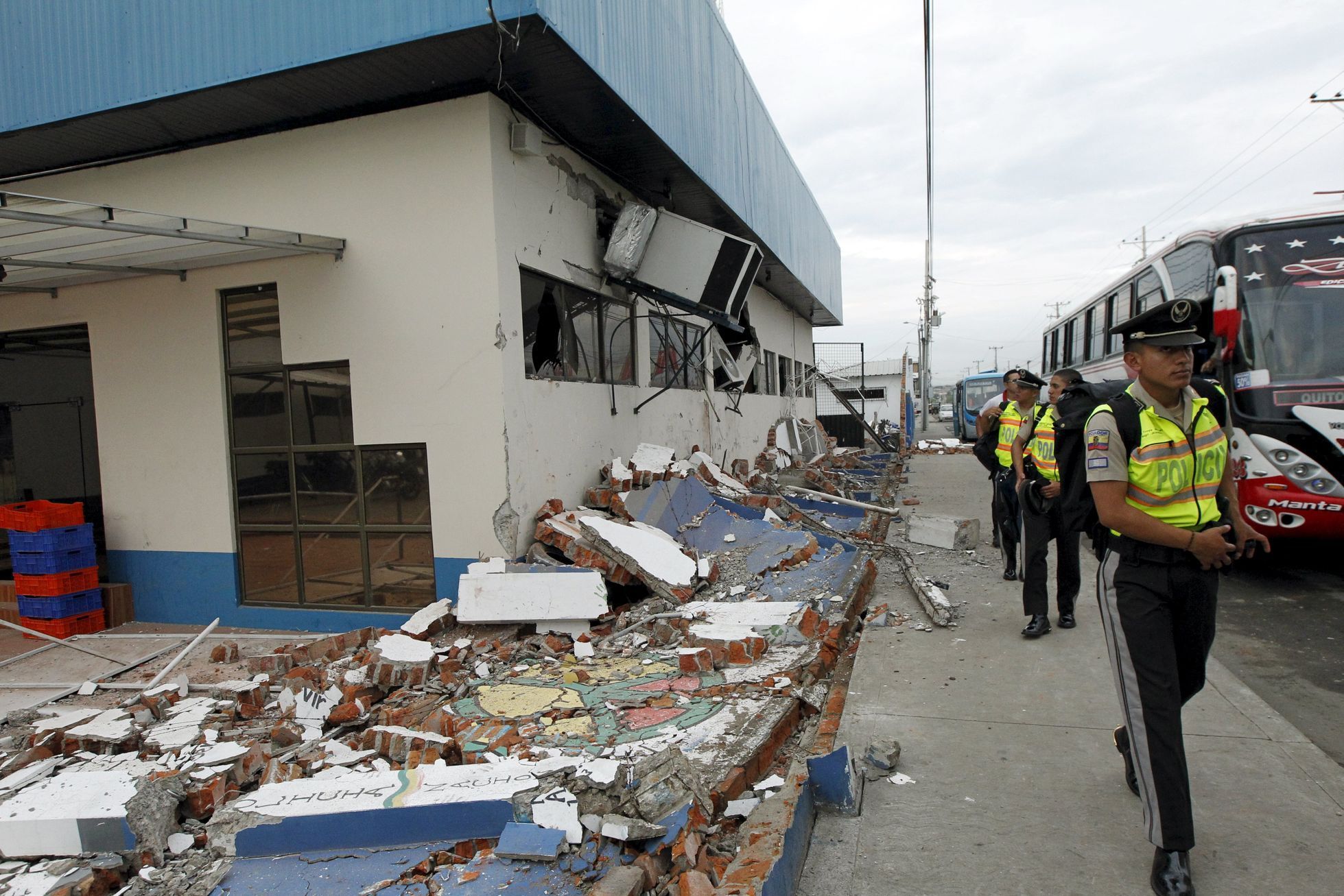 Police officers walk next to debris after an earthquake struck off Ecuador's Pacific coast, at Tarqui neighborhood in Manta