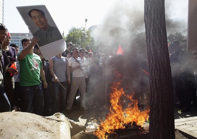 Protesters burn Japanese flags during a protest against Japan's purchase of the disputed Senkaku or Diaoyu islands outside the Japanese embassy in Beijing September 15, 2012. Thousands of protesters besieged the Japanese embassy in Beijing on Saturday, hurling rocks and bottles at the building as police struggled to keep control, amid growing tensions between Asia's two biggest economies over a group of disputed islands. REUTERS/Jason Lee (CHINA - Tags: POLITICS CIVIL UNREST)