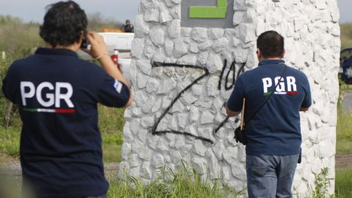 Federální agenti fotí znak drogového kartelu Zetas nedaleko místa, kde našli v plastových pytlích ostatky 50 lidí.