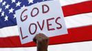 A man holds a sign during a vigil for victims behind the theater where a gunman opened fire on moviegoers in Aurora, Colorado July 22, 2012. Residents of a Denver suburb mourned their dead on Sunday from a shooting rampage by a "demonic" gunman who killed 12 people and wounded 58 after opening fire at a cinema showing the new Batman movie. President Barack Obama headed to Aurora, Colorado, on Sunday to meet families grieving their losses Friday's mass shooting that has stunned the nation and rekindled debate about guns and violence in America. REUTERS/Shannon Stapleton (UNITED STATES - Tags: CRIME LAW) Published: Čec. 23, 2012, 1:35 dop.