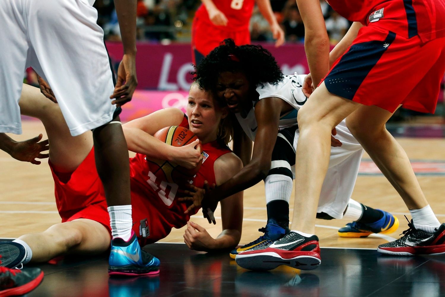 Česká basketbalistka Alena Hanušová bojuje vleže o míč s Angolankou Catarinou Camufalovou v utkání skupiny A na OH 2012 v Londýně.