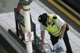 Policista prohledává odloženou tašku na londýnské stanici Aldgate.