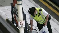 Policista prohledává odloženou tašku na londýnské stanici Aldgate.