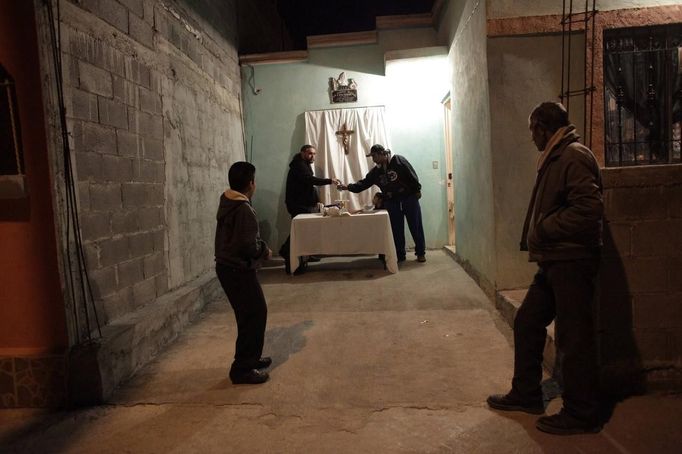 Catholic priest Adolfo Huerta (L rear), known as "Gofo", greets a neighbour before conducting a mass between two houses in Saltillo February 26, 2013. Ordained five years ago, Huerta is an unconventional priest who likes rock music, dyes the ends of his hair red, dresses in black, and enjoys riding his motorcycle. Huerta found God and priesthood while studying philosophy at the Pontifical University in Mexico City and working with HIV-positive patients and sex workers as a social activist. He says it is important to demystify faith and accept people's differences without judgment, and in his sermons he references rock songs, quotes books and tells jokes. Picture taken February 26, 2013. REUTERS/Daniel Becerril (MEXICO - Tags: RELIGION SOCIETY) ATTENTION EDITORS: PICTURE 9 OF 26 FOR PACKAGE 'CHURCH, FAITH AND ROCK'N ROLL' SEARCH 'PRIEST DANIEL' FOR ALL IMAGES Published: Bře. 15, 2013, 10:23 dop.