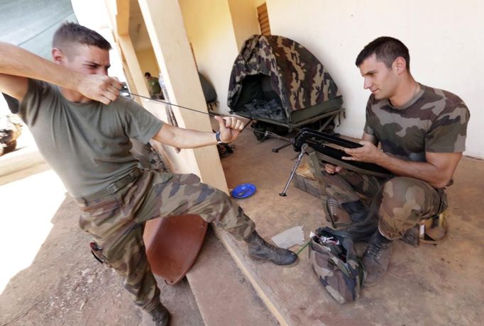 A French soldier helps another to clean his weapon at the Mali air force base near Bamako as troops await their deployment January 18, 2013. REUTERS/Eric Gaillard (MALI - Tags: CIVIL UNREST CONFLICT MILITARY) Published: Led. 18, 2013, 6:10 odp.