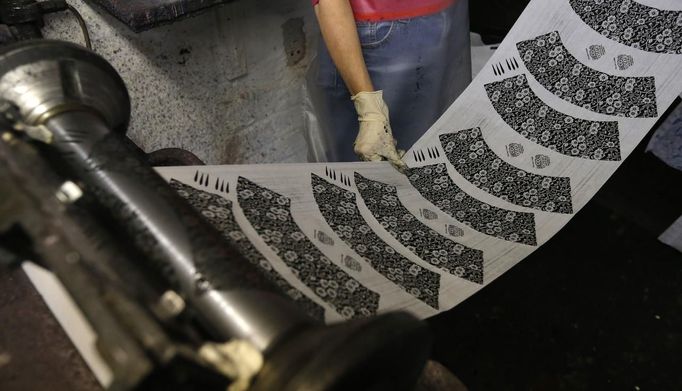 A worker removes sheets of tissue paper from a machine in a workshop at the Middleport pottery in Stoke-on-Trent, central England January 22, 2013. The pottery which dates back to 1888 and was rescued from closure in 2009, continues to use traditional methods to produce its range of ceramics and famous Burleigh Ware pottery. REUTERS/Phil Noble (BRITAIN - Tags: BUSINESS EMPLOYMENT SOCIETY) Published: Led. 22, 2013, 4:46 odp.