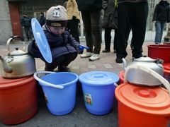 Dítě si v čínském Charbinu prohlíží kbelíky s vodou.