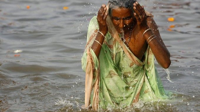 Během koupele v silně znečištěné, avšak posvátné řece si poutníci opakují modlitby z hinduistických svatých knih