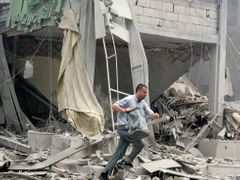 Muž utíká během leteckého poplachu z trosek domu v libanonském Bejrútu.