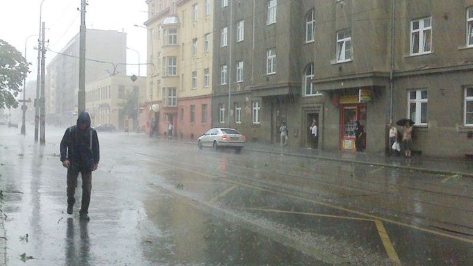 Prudký déšť zanechal na ulicích sloupec vody, který nestíhal odtéce. Praha, 23. července po páté hodině večerní.