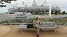 A soldier looks at his mobile phone as he sits near the Olympic Stadium at the Olympic Park in Stratford, the location of the London 2012 Olympic Games, in east London July 16, 2012. The first wave of Olympic athletes and visitors began pouring into Britain on Monday and officials played down fears that a packed London would buckle under the pressure of its biggest peacetime security and transport operation. An embarrassing shortage of security guards, fears over airport queues and questions about the capital's creaking transport system have overshadowed preparations for the Games. REUTERS/Suzanne Plunkett (BRITAIN - Tags: SPORT OLYMPICS MILITARY) Published: Čec. 16, 2012, 3:38 odp.