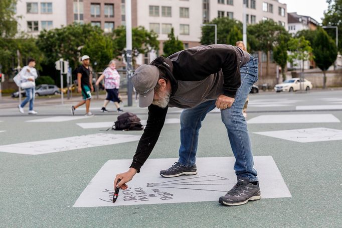 Na snímku Dan Perjovschi z Rumunska svým dílem Horizontal Newspaper pomalovává náměstí Rainer-Dierichs-Platz.