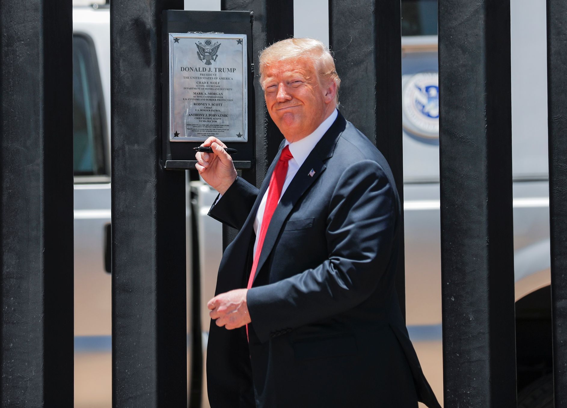 Trump podepisuje plaketku na 320. kilometru zdi na hranici s Mexikem.
