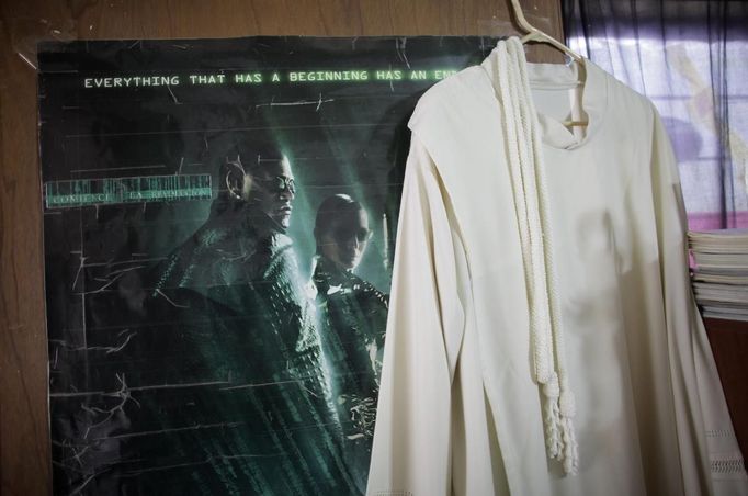 The robe of Catholic priest Adolfo Huerta, known as "Gofo", hangs next to a poster of the movie Matrix in Saltillo February 22, 2013. Ordained five years ago, Huerta is an unconventional priest who likes rock music, dyes the ends of his hair red, dresses in black, and enjoys riding his motorcycle. Huerta found God and priesthood while studying philosophy at the Pontifical University in Mexico City and working with HIV-positive patients and sex workers as a social activist. He says it is important to demystify faith and accept people's differences without judgment, and in his sermons he references rock songs, quotes books and tells jokes. Picture taken February 22, 2013. REUTERS/Daniel Becerril (MEXICO - Tags: RELIGION SOCIETY) ATTENTION EDITORS: PICTURE 21 OF 26 FOR PACKAGE 'CHURCH, FAITH AND ROCK'N ROLL' SEARCH 'PRIEST DANIEL' FOR ALL IMAGES Published: Bře. 15, 2013, 10:24 dop.