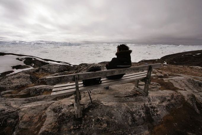 Průvodkyně Vilhelmina Nathanielsenová sedí na lavičce a pozoruje fjord Jakobshavn nedaleko grónského Ilulissatu. Grónsko je největší ostrov světa a většina jeho povrchu je pokryta ledem, kterého je více než 2,6 milionu metrů krychlových, což je zhruba desetina zásob veškeré sladké vody na světě.