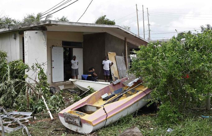 Residents of Caribbean Terrace in southern Kingston survey the damage and the boats washed up onto their lawn by Hurricane Sandy, October 25, 2012. Strengthening rapidly after tearing into Jamaica and crossing the warm Caribbean Sea, Sandy hit southeastern Cuba early on Thursday with 105-mph winds that cut power and blew over trees, with at least three fatalities in Jamaica and Haiti. REUTERS/Gilbert Bellamy (JAMAICA - Tags: ENVIRONMENT DISASTER) Published: Říj. 25, 2012, 5:45 odp.