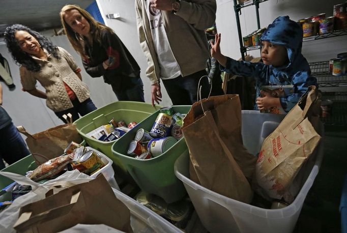 Jaidon Santos-Volpe answers questions as he helps fill bins at a food pantry as his two mothers Theresa Volpe and Mercedes Santos look on in Evanston, Illinois, December 28, 2012. Santos and Volpe are a same-sex couple raising two of their biological children as they struggle to get same-sex marriages passed into law in Illinois. Picture taken December 28, 2012. REUTERS/Jim Young (UNITED STATES - Tags: SOCIETY) Published: Bře. 25, 2013, 6:08 odp.