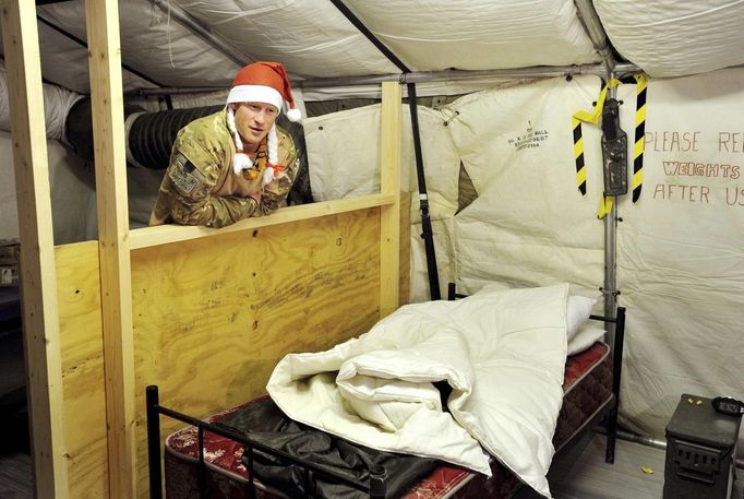 Britain's Prince Harry wears a Santa Claus hat as he shows media his sleeping area and bed at the VHR (very high readiness) tent at Camp Bastion, southern Afghanistan in this photograph taken December 12, 2012, and released January 21, 2013. The Prince, who is serving as a pilot/gunner with 662 Squadron Army Air Corps, is on a posting to Afghanistan that runs from September 2012 to January 2013. Photograph taken December 12, 2012. REUTERS/John Stillwell/Pool (AFGHANISTAN - Tags: MILITARY POLITICS SOCIETY ROYALS CONFLICT) Published: Led. 21, 2013, 7:41 odp.