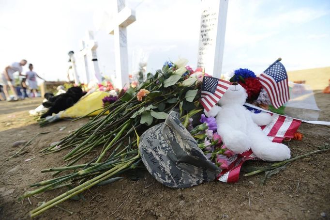 A signed military hat lies at the base of a cross dedicated to Air Force member Jesse Childress during a vigil at the Aurora Municipal Center for the people killed by a gunman last Friday in the Century 16 movie theater in Aurora, Colorado, July 22, 2012. Residents of a Denver suburb mourned their dead on Sunday from a shooting rampage by a gunman who killed 12 people and wounded 58 after opening fire at a cinema showing the new Batman movie. REUTERS/Jeremy Papasso (UNITED STATES - Tags: CRIME LAW CIVIL UNREST OBITUARY MILITARY) Published: Čec. 23, 2012, 4:01 dop.