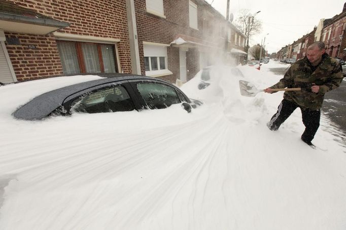 A man shovels snow off his car in a street of Cambrai, northern France, March 12, 2013 as winter weather with snow and freezing temperatures returns to northern France. REUTERS/Pascal Rossignol (FRANCE - Tags: ENVIRONMENT) Published: Bře. 12, 2013, 1:52 odp.