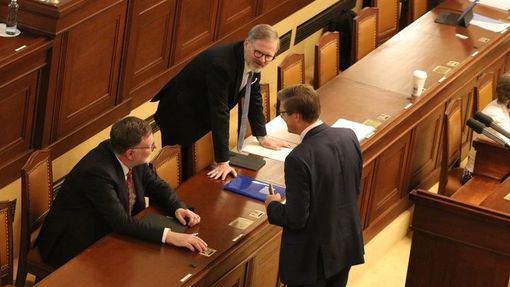 Premiér a jeho dva ministři se radí před hlasováním o návrhu Pirátů, aby se jednání účastnil i Pavel Blažek. Kolem hlasování bylo dost rušno, nakonec ale návrh prošel.
