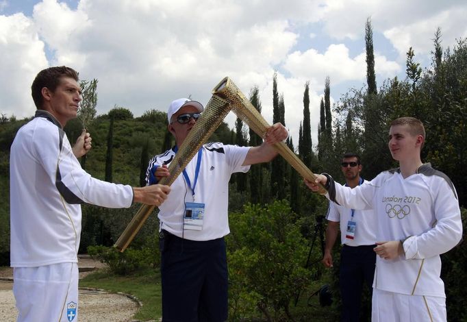 Spyridon Gianniotis (L), Greece's world champion of swimming, lights the torch held by Alexander Loukos (R), British boxer of Greek descent, during the Olympic torch relay at the site of ancient Olympia in Greece May 10, 2012. REUTERS/John Kolesidis (GREECE - Tags: SPORT OLYMPICS) Published: Kvě. 10, 2012, 9:54 dop.